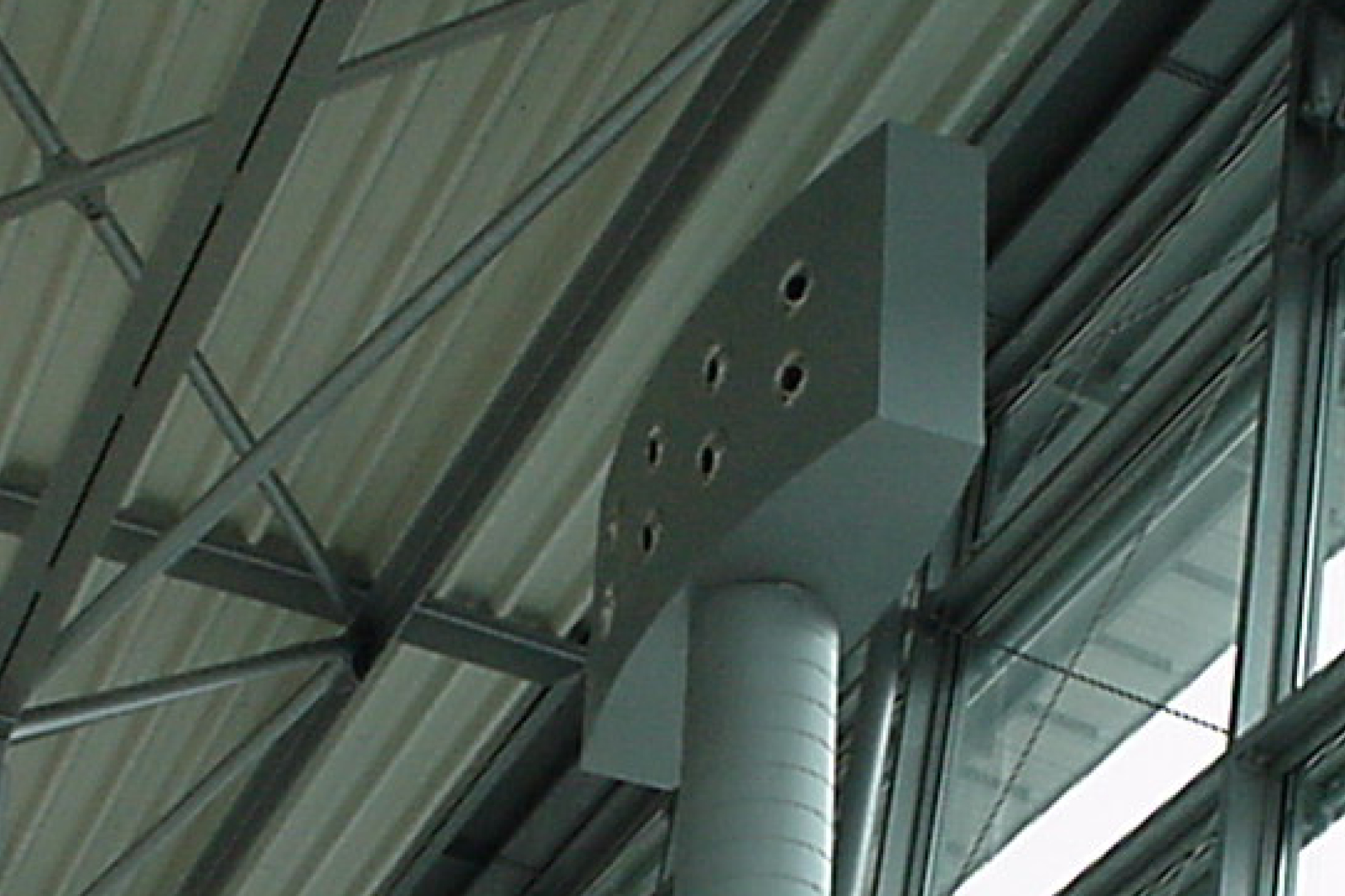 Lüftungsanlage in einer Industriehalle mit großem Abluftrohr und Metallkonstruktion an der Decke.