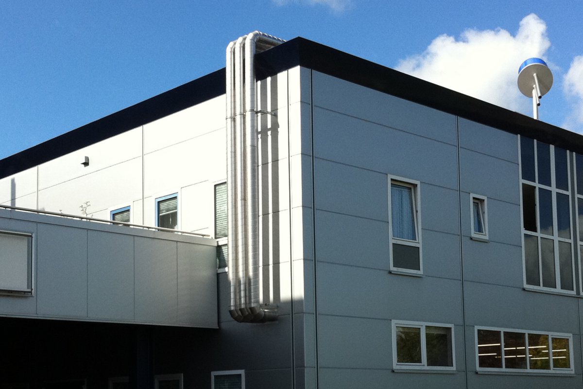 Moderne Gewerbeimmobilie mit installierten Lüftungsrohren an der Fassade – Teil einer Klimaanlagen- und Gebäudetechnikinstallation.